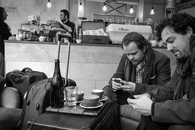 Velthy and Silvan on their mobile while waiting of a delicious cafe in London